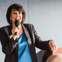 President Mantella smiling as she speaks to GVSU Alumni in D.C., arm rested on podium